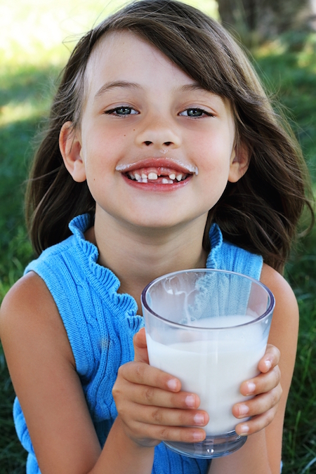 little girl with tooth gap drinking milk